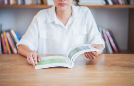 Asian woman sitting at the table with reading a book in library.の写真素材