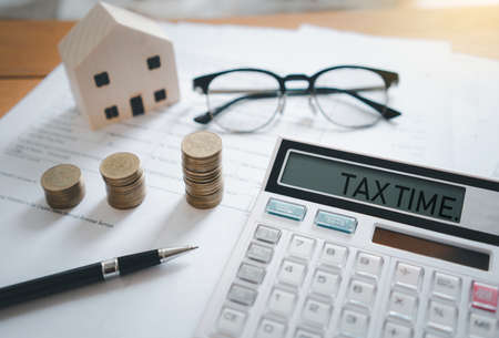 Stacked of Coins with calculator,House model,tax form,glasses and pen,Income Tax Raise Concept.の写真素材
