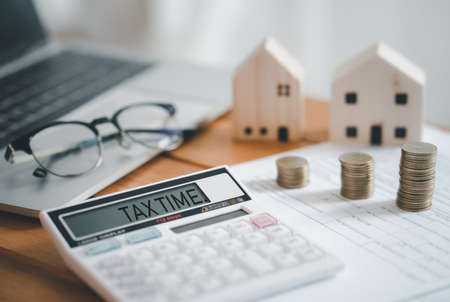 Stacked of Coins with calculator,House model,tax form,glasses and tablet,Income Tax Raise Concept.の写真素材