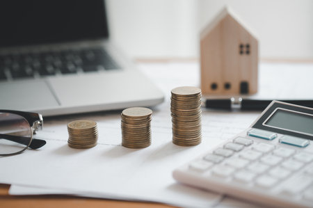 Stacked of Coins with calculator,House model,tax form,glasses and tablet,Income Tax Raise Concept.の写真素材