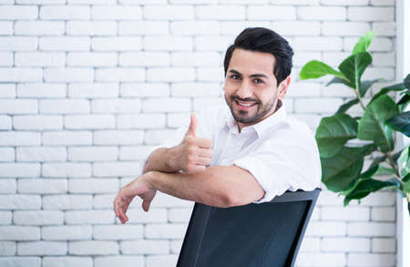 Cheerful businessman showing thumbs up and smiling at camera.の写真素材