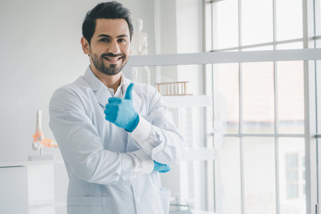 Smiling doctor posing with arms crossed and looking at camera in medical office.の写真素材