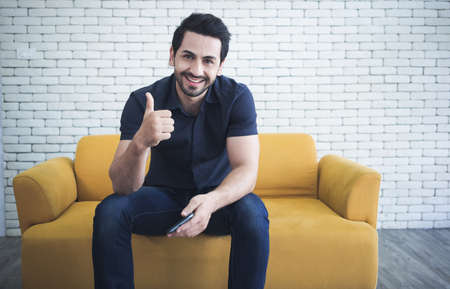 Portrait of handsome man showing thumbs up and smiling at camera.の写真素材