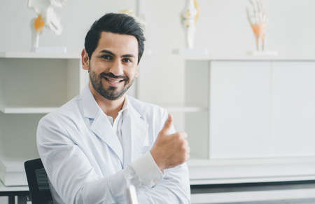 Smiling doctor posing with arms crossed and looking at camera in medical office.の写真素材