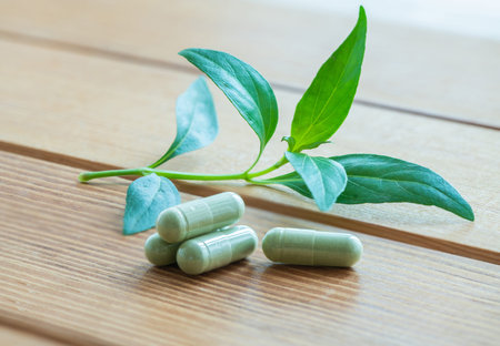 Herb capsule with green herbal leaf on wood,Andrographis paniculata herbal antipyretic capsules.の写真素材