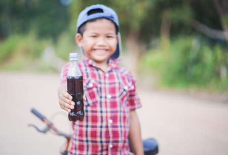 Little boy holding sparkling water bottle after mini cycling.