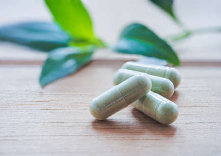 Herb capsule,Andrographis paniculata herbal antipyretic capsules on wooden.の写真素材