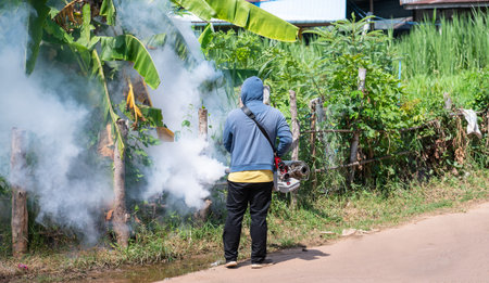 Worker fogging machine spraying smoke to eliminate mosquitoes.Prevention of epidemics in the rainy season and general location in community.の写真素材