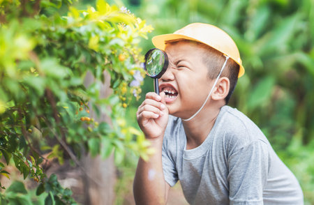 Happy asian kid looking at leaves and holding magnifying glass for explore.の写真素材