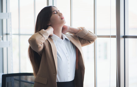 Young asian woman tired and massaging neck pain in office.の写真素材