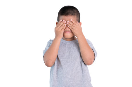 Playful shy asian boy covering his face and smiling ,isolated on white background.の写真素材