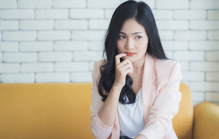 Portrait of asian woman thinking and touching herself face by finger.の写真素材