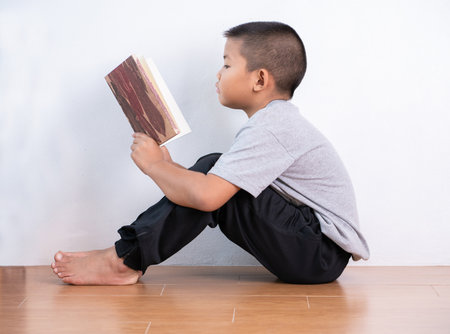 Asian boy reading a book in home.He sitting on the floor.の写真素材