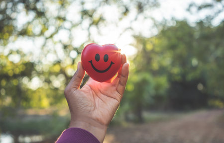 Woman hand holding red heart and smile face.Health care and love concept.の写真素材