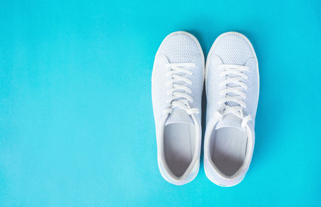 Pair of white female fashion sneakers on blue background.Top view.の写真素材