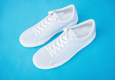 Pair of white female fashion sneakers on blue background.Top view.の写真素材