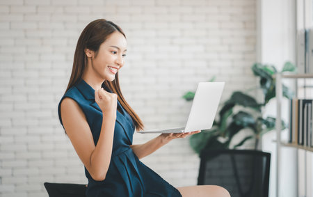 Portrait of happy excited successful businesswoman, Looking at laptop with showing triumphing  in office.の写真素材