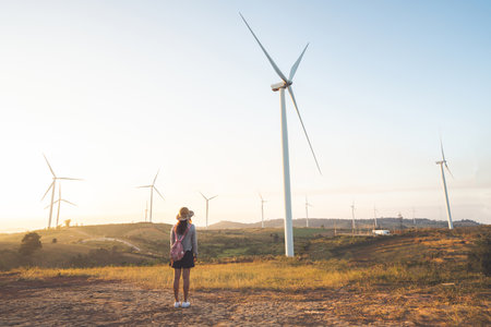 Woman tourist standing and looking at a beautiful view of wind turbine.Windmills for electric power production.の写真素材