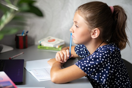 Distance learning online. Schoolgirl with a computer. The girl carefully looks at the monitor and...