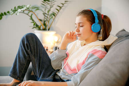 Teenage girl with closed eyes in headphones listening to music, music brings pleasure and relaxation, lifestyleの写真素材
