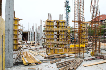 Concrete pillars supported with yellow boards and metal rods on construction siteの写真素材