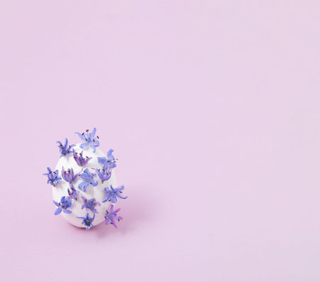 Creative layout with white egg and wild violet flowers. Minimal Easter concept.