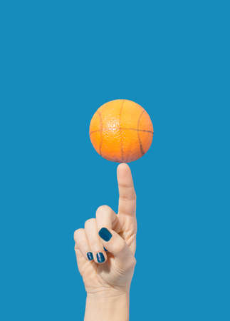 Rotating orange on a finger on the blue background. Basketball themed concept.の写真素材