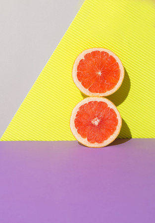 Two bright grapefruit slaces againt vibrant background. Trendy sunlight Summer conceptの写真素材