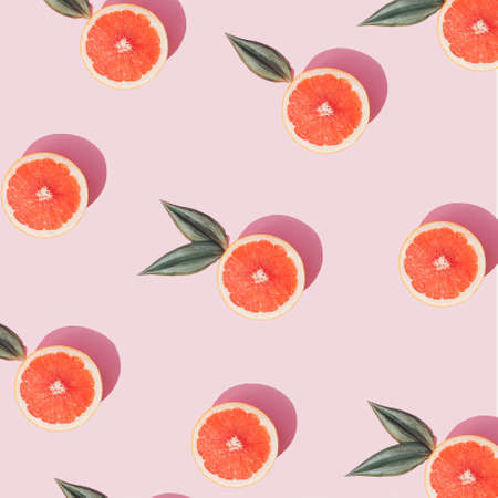 Trendy Summer arangement made with fresh grapefruit slices on pastel pink background. Creative flat lay.の写真素材