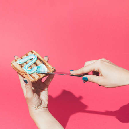 Creative scene of female hands putting a tooth paste on toast bread. Minimal concept.の写真素材