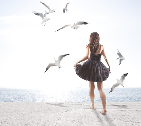 Young girl with seagulls, freedom conceptの写真素材