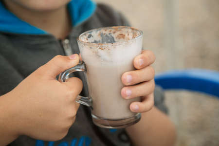 a large Cup of cocoa with milk in the hands of a childの写真素材