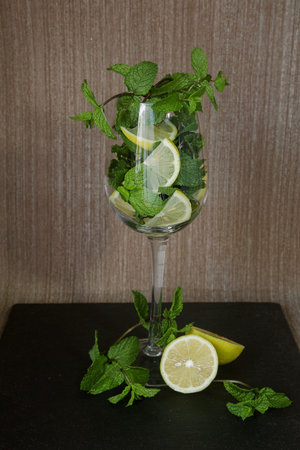 sliced lemon with mint sprigs in a long stemmed glass. High quality photo