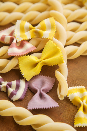 dry multicolored Italian handmade macaroni, close-up on a log cabin and a wooden table.