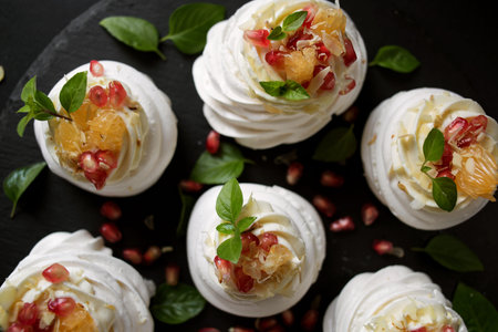 dessert called Anna Pavlova. Meringue with cream garnished with pomegranate, tangerine slices and...
