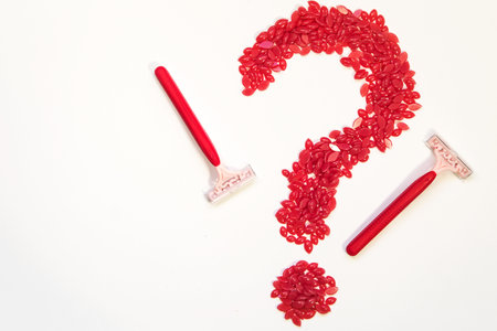 wax for hair removal in granules is laid out in the form of a question mark, there are shaving machines nearby.の写真素材