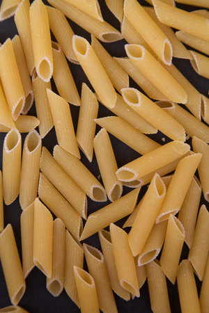 Italian Penne pasta close-up on a black background.