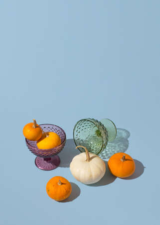 Colorful halloween pumpkins and ice cream glasses against pastel blue background. Thanksgiving minimal still life conceptの写真素材