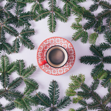Red mug or cup with coffe or hot drink in the center of fir tree branch on a white background....