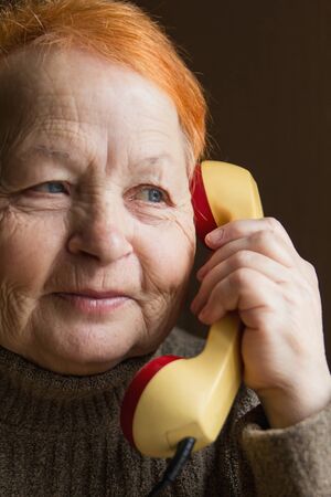 Elderly woman is talking on the phone. Retro. Close-up.の写真素材