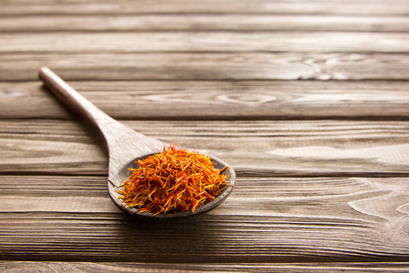 Spice saffron in wooden spoon on wooden table. Close-up.の写真素材