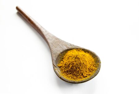 Powder curry in a wooden spoon on a white background. Close-up.の写真素材