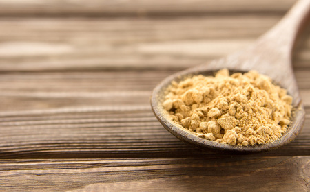 Ginger powder in wooden spoon on wooden table. Close-up.の写真素材