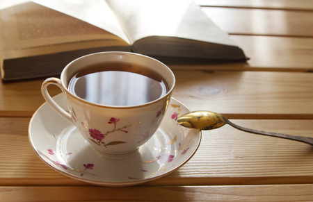 cup of tea and book on wooden table, lit by the sun. Close-up.の写真素材