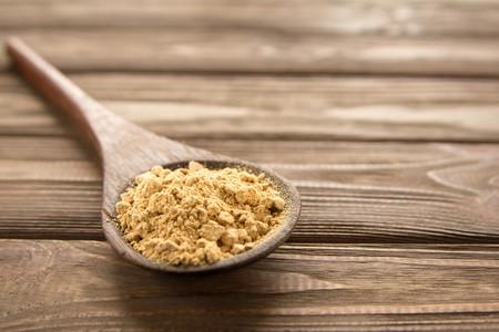 Ginger powder in wooden spoon on wooden table. Close-up.の写真素材