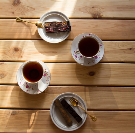 cup of tea and chocolate on wooden table, lit by the sun. Top view. Close-up.の写真素材