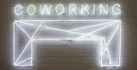 White glowing light Â«COWORKINGÂ» Neon sign against a brick backgroundの写真素材