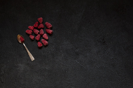 Frozen berries of raspberries on silver spoon on black concrete  background, copy space for text or inscription. Healthy food idea. Top view.の写真素材