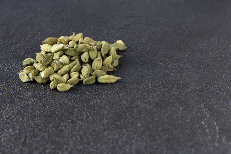 Green cardamom pods on a black stone background. Pile of green Cardamom, cardamon or cardamum (dried fruits of Elettaria cardamomum).の写真素材