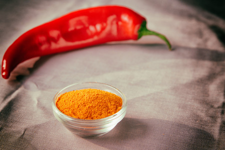 Red hot chilli pepper and pepper powder for cooking food on linen gray tablecloth. Healthy eating. Close-up.の写真素材